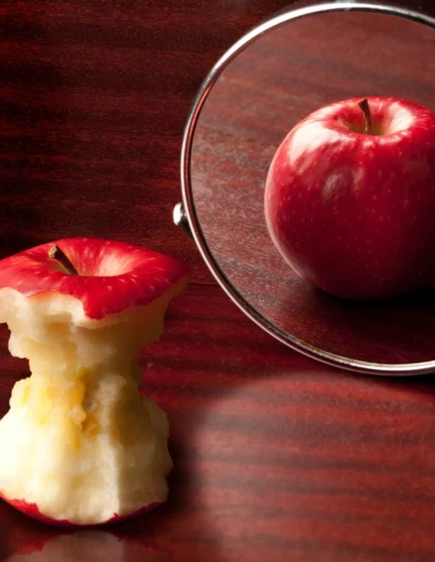 Manzana mordida y reflejo en espejo.